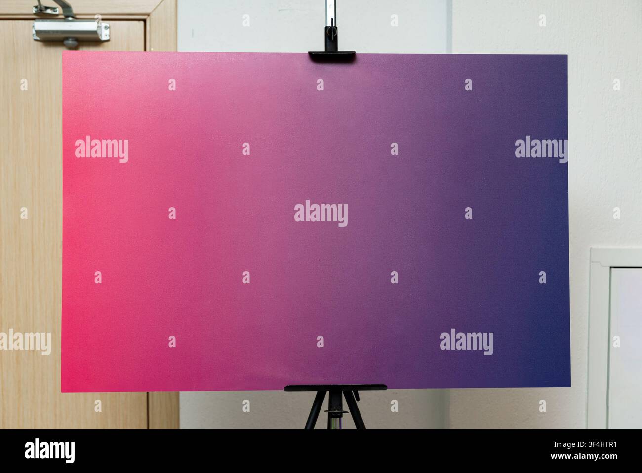 Un grand tableau artistique présentant un dégradé fluide qui passe du rose à gauche au violet à droite est affiché sur un trépied. Le fond Banque D'Images