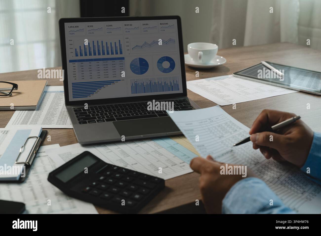 homme vérifie des tableaux financiers sur le tableau de bord d'un ordinateur portable, calculatrice,, document financier vérifiant des chiffres avec un stylo pour soutenir la vérification des documents, rep Banque D'Images