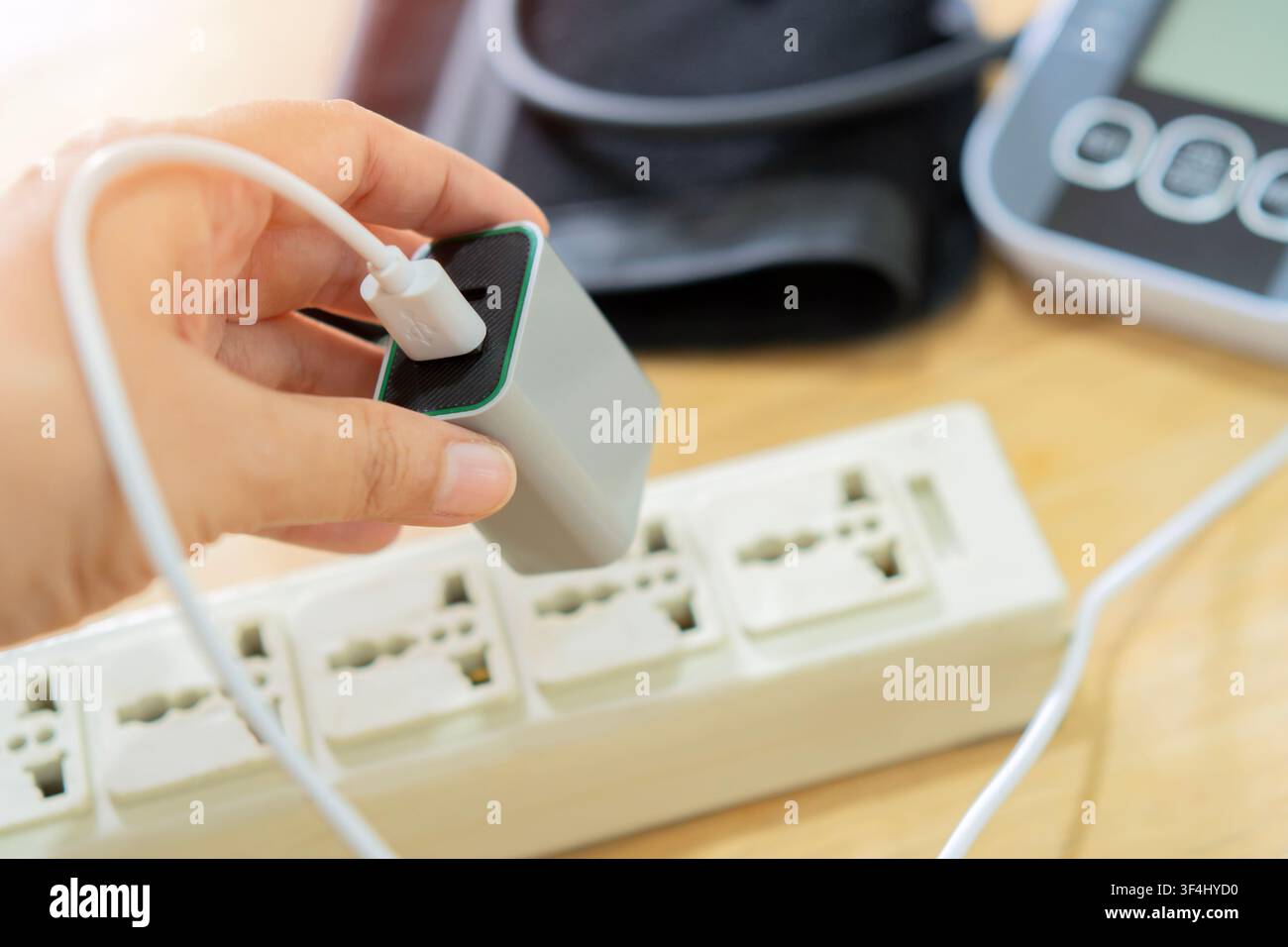 Grossissement d'une femme connectant un adaptateur d'alimentation à une prise pour utiliser le moniteur de tension artérielle. Concept de recharge des appareils et de consommation électrique Banque D'Images