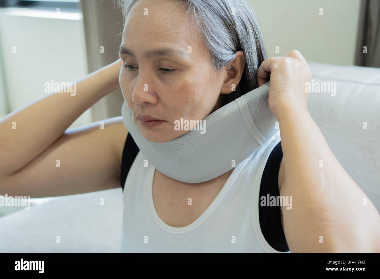 Femme asiatique mûre portant un col orthopédique souffrant de douleurs au cou suite à un accident. Concept de douleur au cou. Concept de Neckache. Banque D'Images