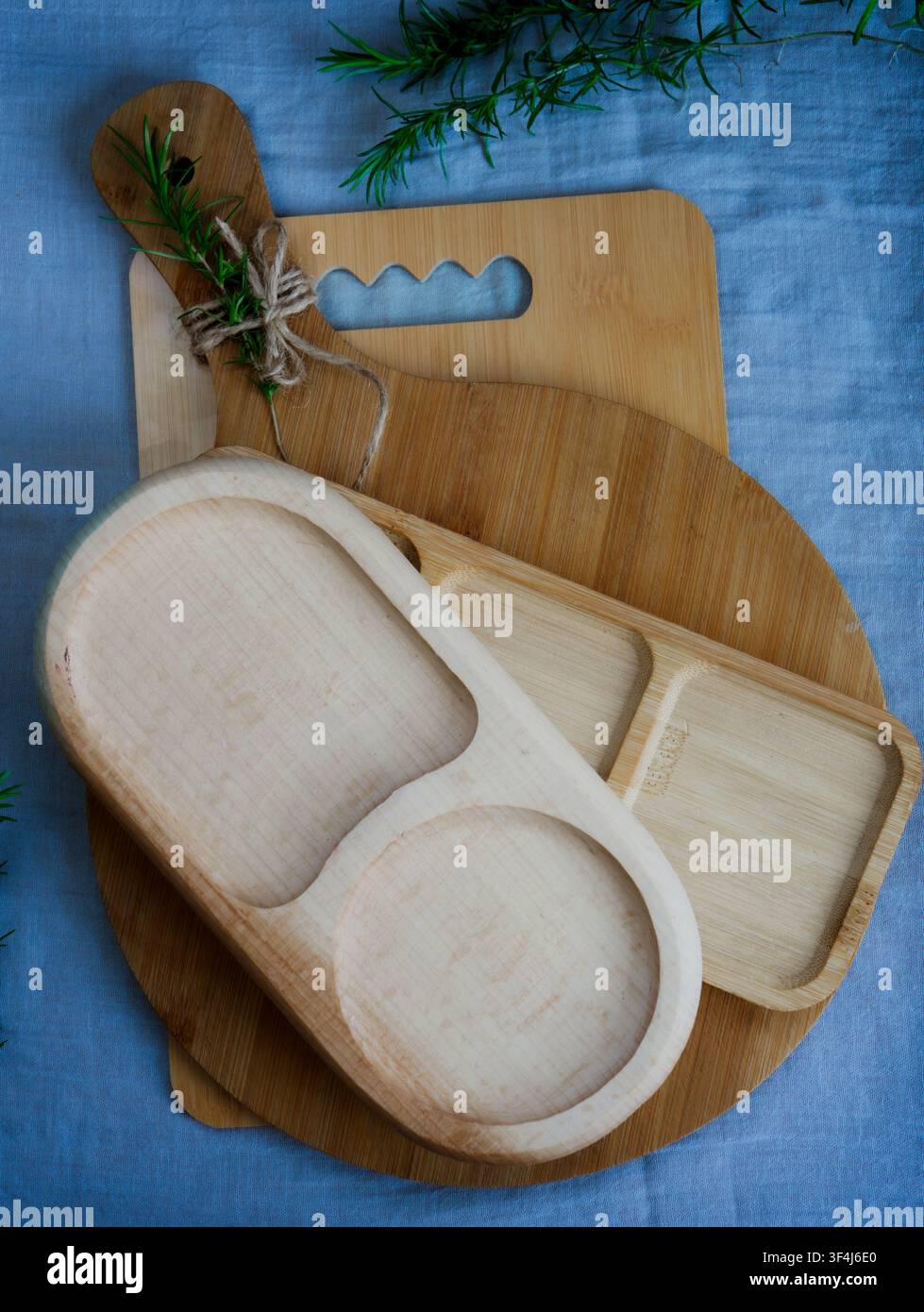 Plateau de service en bambou vide à trois compartiments posé sur une planche à découper ronde en bois sur un tissu en lin clair. Vaisselle de table minimaliste avec copie Banque D'Images