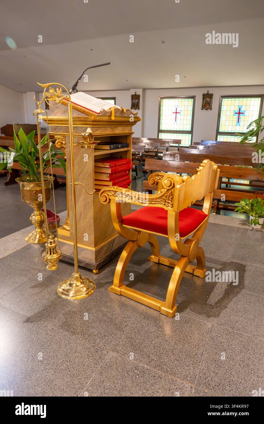 Chaire dorée avec un livre, un microphone et une chaise ornée debout dans l'intérieur d'une église Banque D'Images