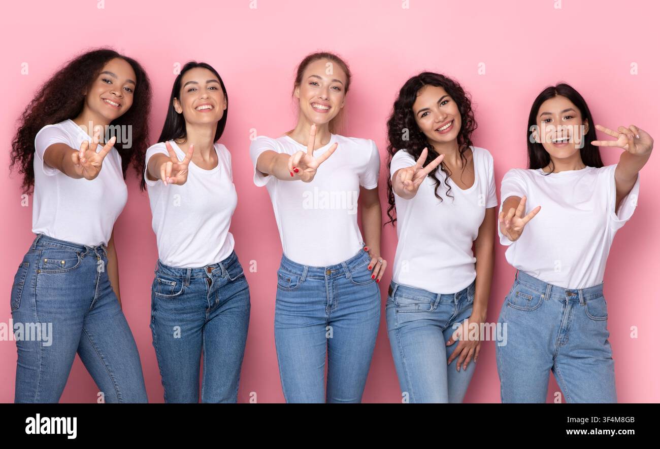 Succès multiracial femmes gestante victoire signe sur Pink Studio fond Banque D'Images