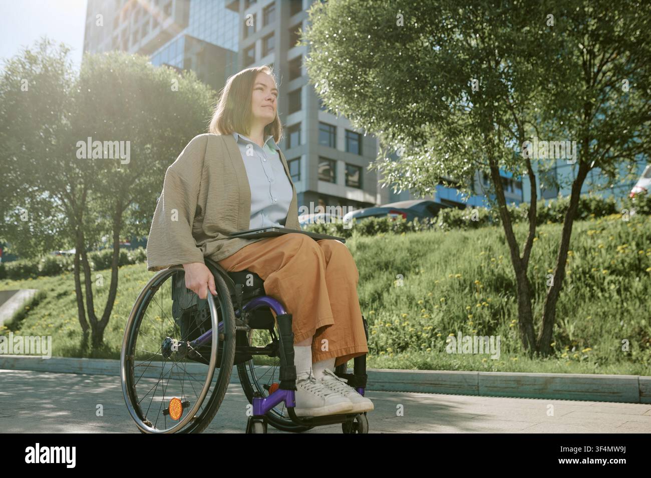 Femme en situation de handicap utilisant un fauteuil roulant dans un parc urbain Banque D'Images