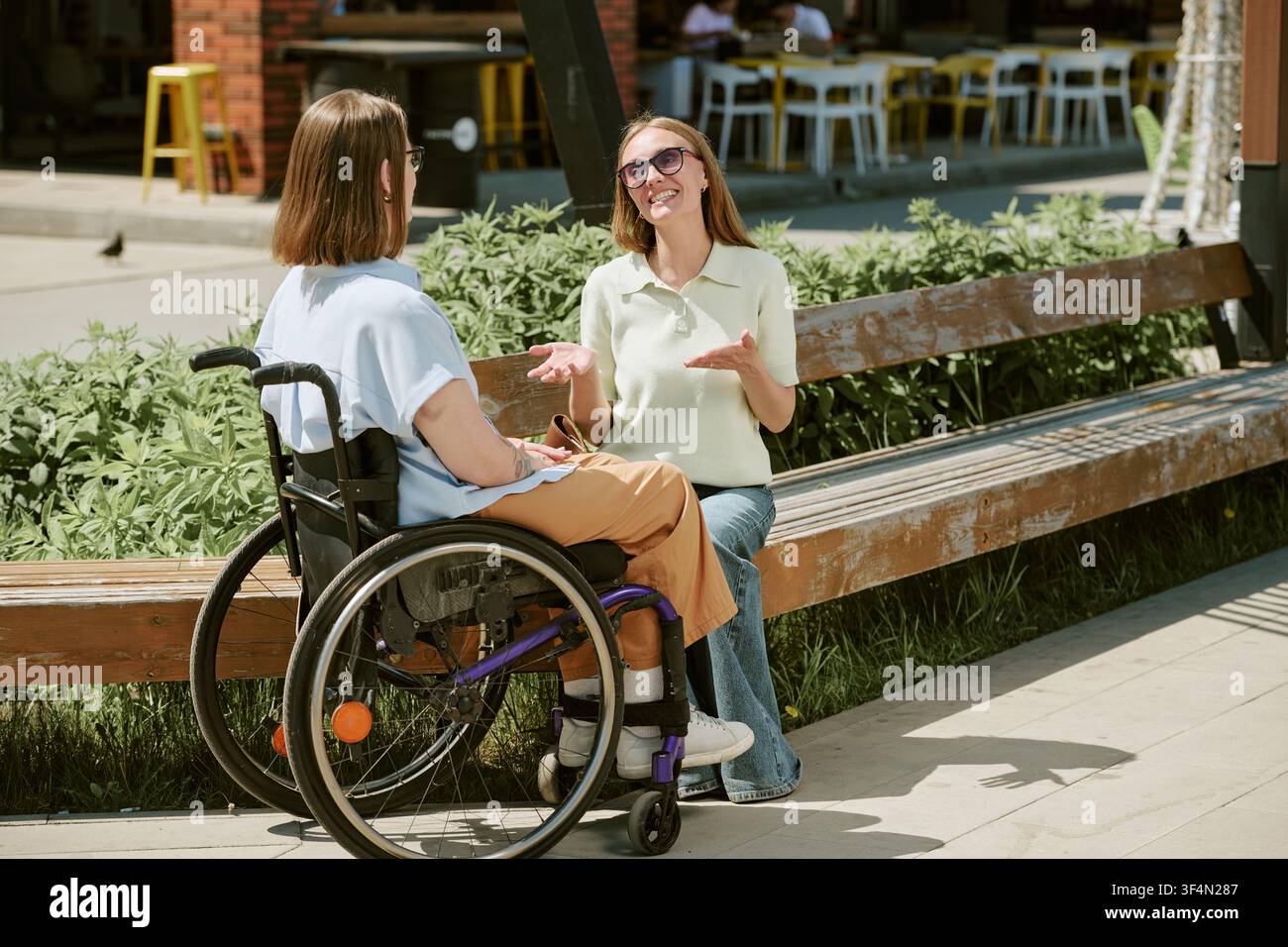 Femme en situation de handicap discutant avec une amie dans un cadre inclusif en plein air Banque D'Images