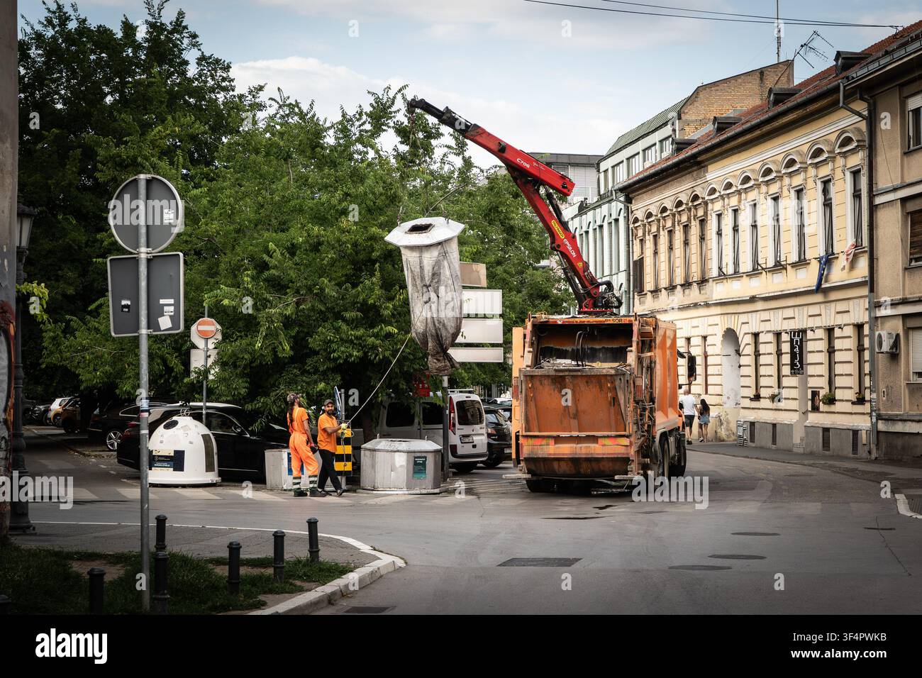 NOVI SAD, SERBIE - 5 JUILLET 2026 : Les agents d'assainissement municipaux de Novi Sad opèrent un camion poubelle avec une grue hydraulique lors de la collecte des déchets par un Banque D'Images