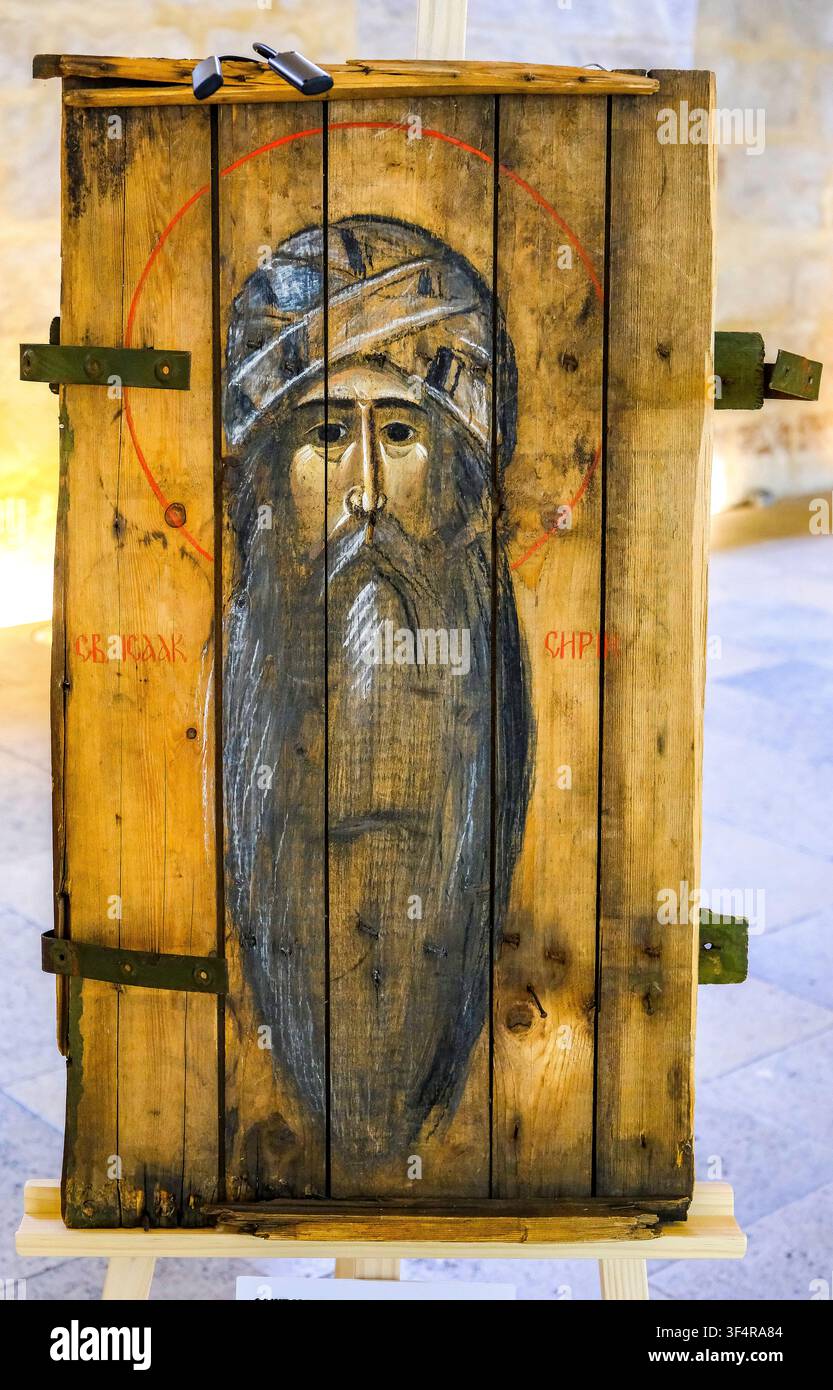 Icône peinte sur bois représentant le visage de saint Isaac, avec un halo rouge et des inscriptions en cyrillique. L'icône est montée sur un fragment de munition Banque D'Images