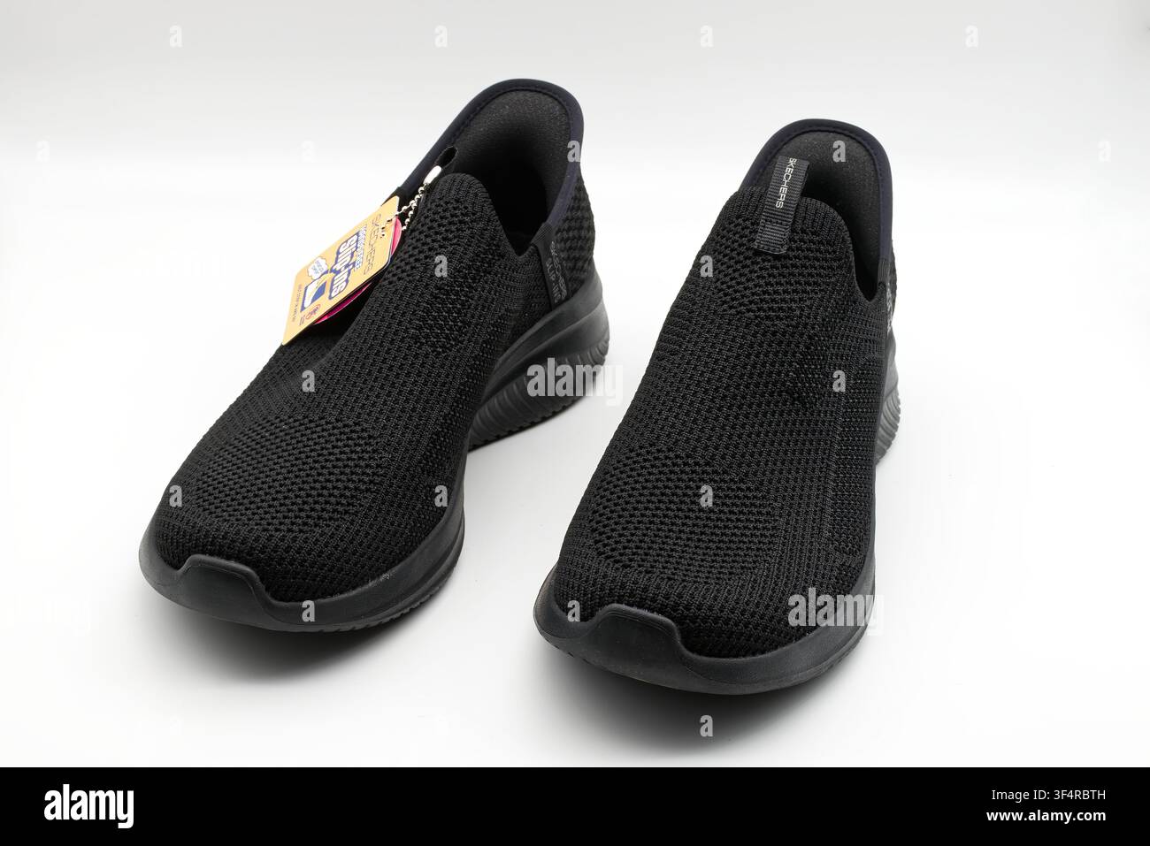 Paire de baskets noires confortables en maille avec étiquette sur fond blanc. Banque D'Images