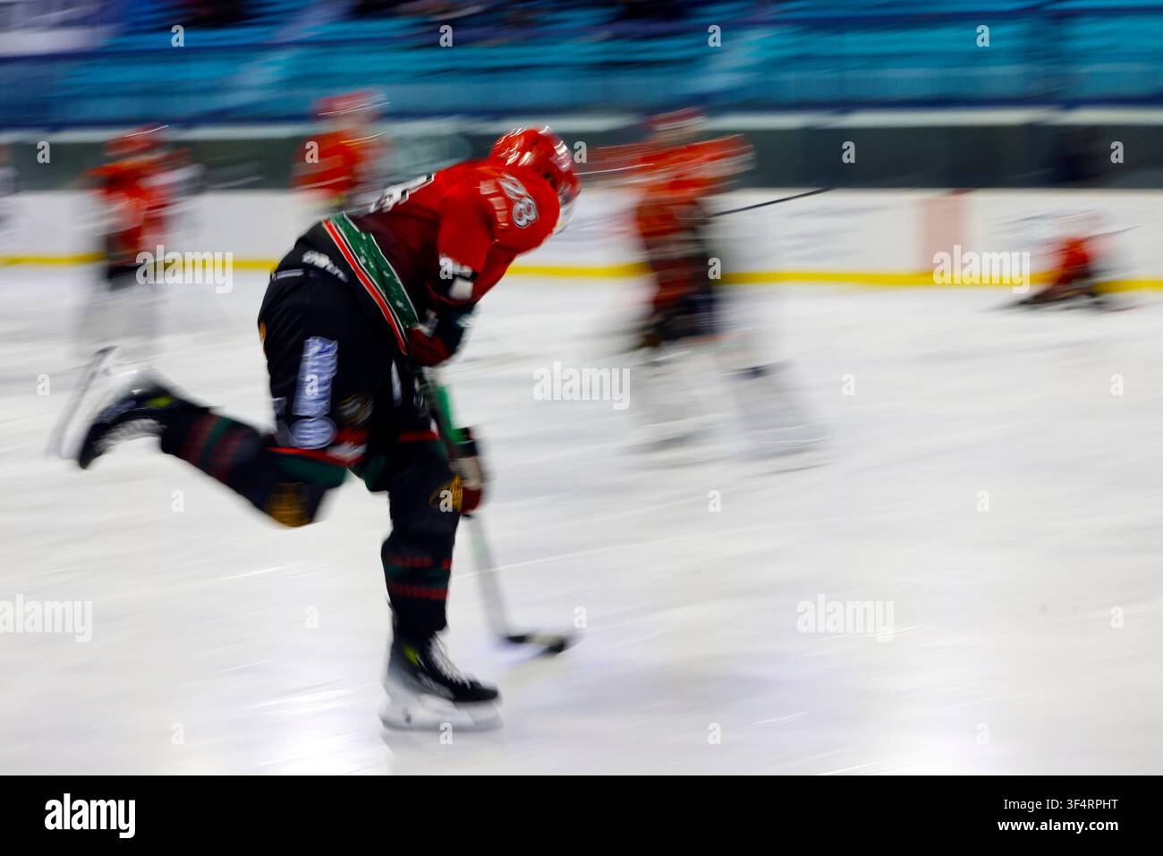 Un joueur de hockey sur glace dans un maillot rouge et noir patinant rapidement sur la glace. Banque D'Images