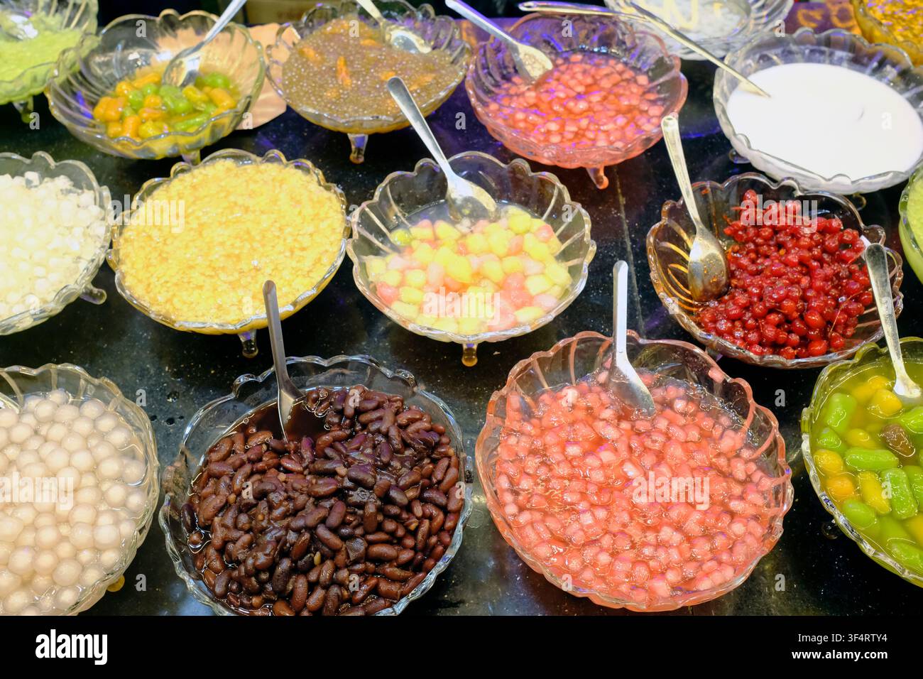 Un assortiment coloré de desserts asiatiques, y compris des fruits, des haricots rouges et des perles de tapioca. Hoa Lu, Vietnam. Banque D'Images