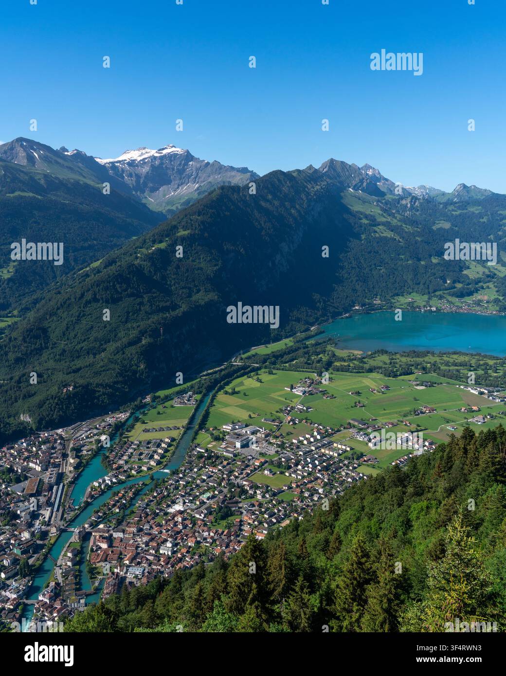Vue du Harder Kulm sur la ville d'Unterseen, la rivière Aare et le lac de Thoune nichés parmi les Alpes suisses sous un ciel bleu clair. Unterseen, C Banque D'Images