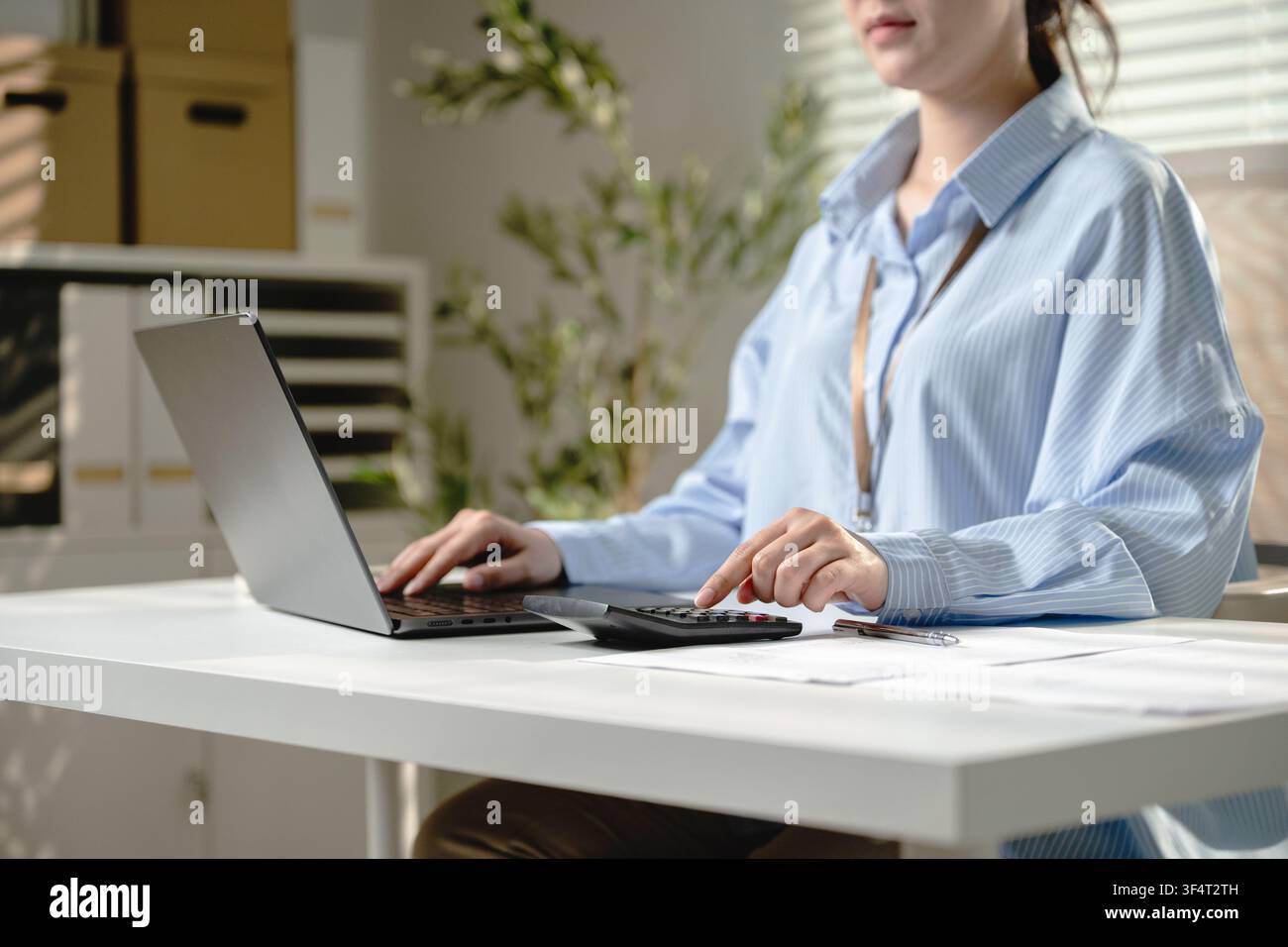 Employé asiatique appuyant sur le bouton de la calculatrice pour les documents d'audit travaillant à son bureau à domicile. Concept de travail à distance préparation de la déclaration de taxes et audit budgétaire Banque D'Images