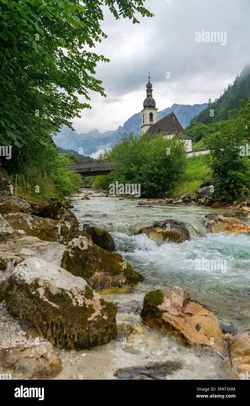 Église du village à Ramsau avec ruisseau de montagne dans les Alpes de Berchtesgaden, Bavière, Allemagne Vertical Banque D'Images