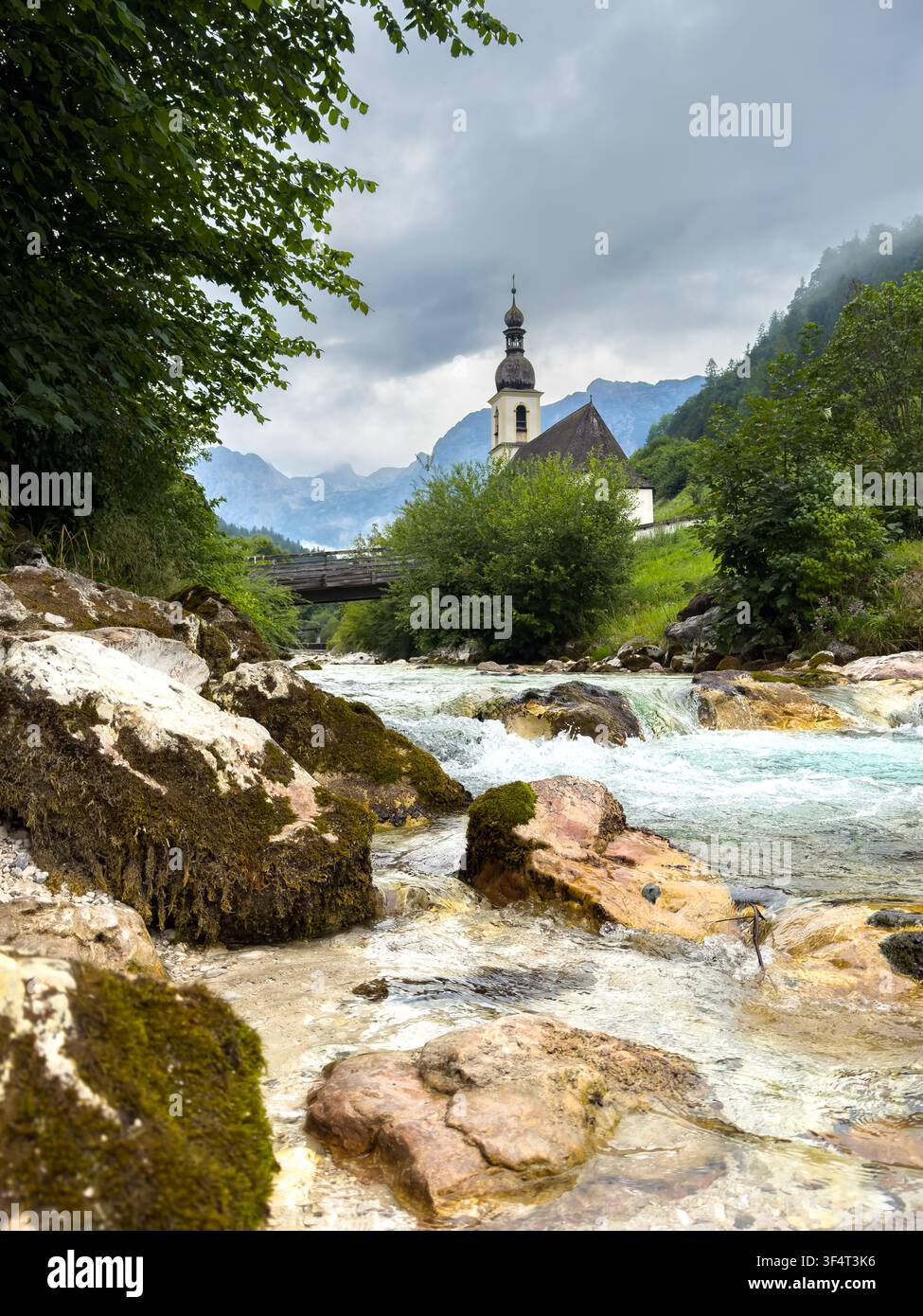 Église du village à Ramsau avec ruisseau de montagne dans les Alpes de Berchtesgaden, Bavière, Allemagne Vertical Banque D'Images