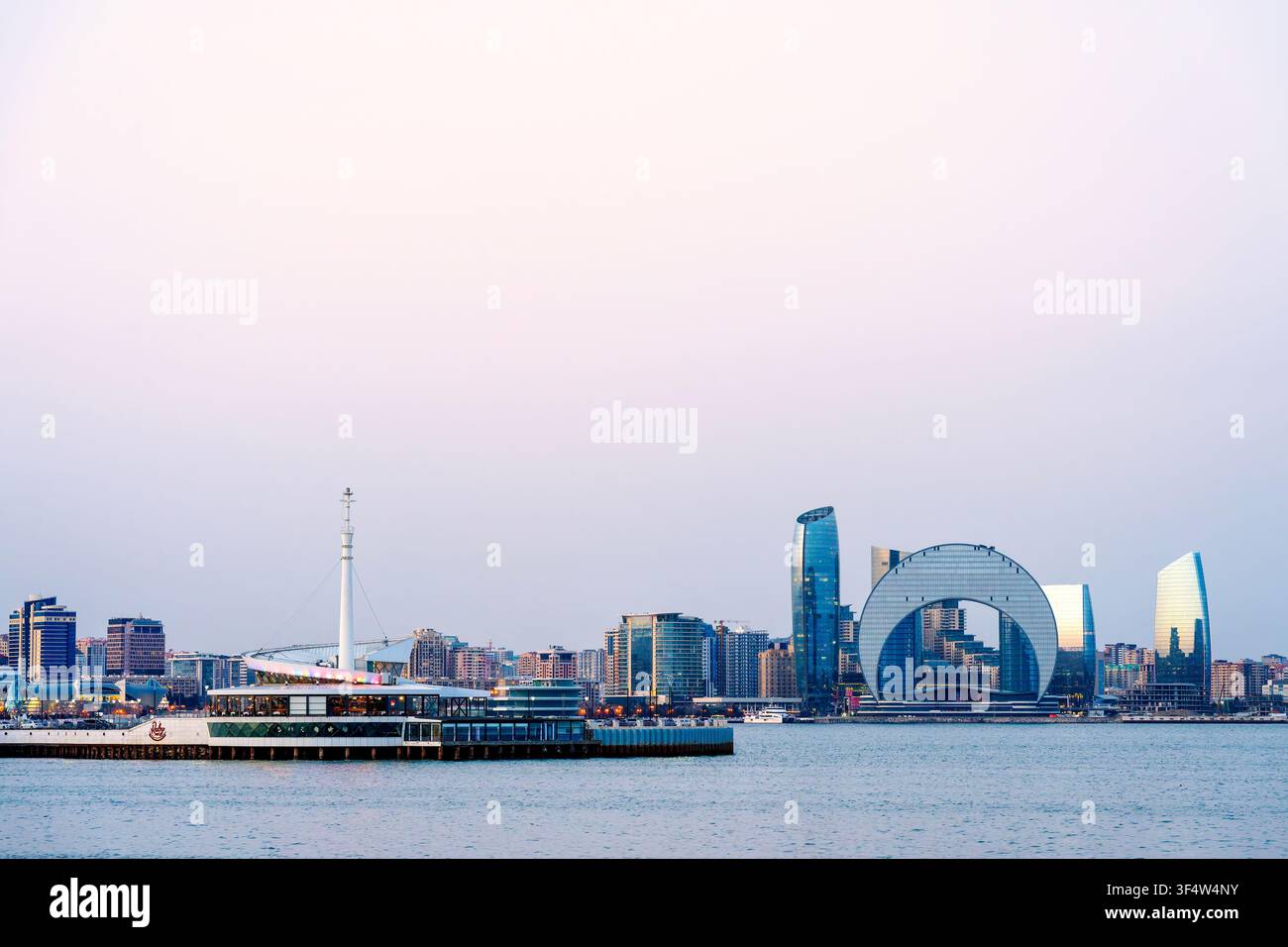 Restaurant flottant Ruby 360 sur la mer Caspienne avec le Crescent Hotel et la tour Port Baku sur le front de mer de Bakou au crépuscule. Bakou, Azerbaïdjan. Banque D'Images