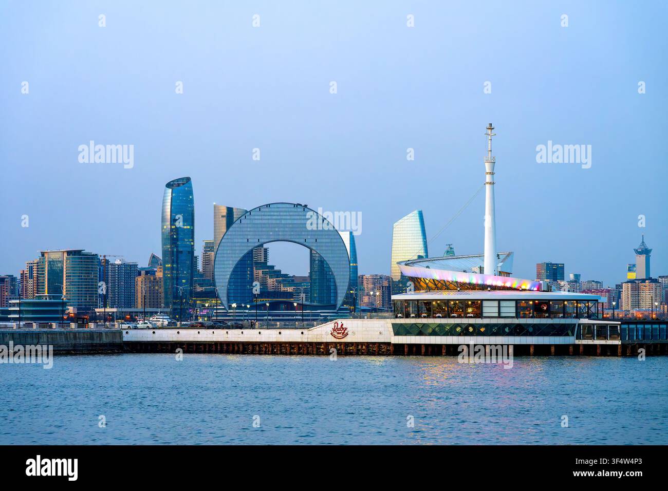 Restaurant flottant Ruby 360 sur la mer Caspienne avec le Crescent Hotel et la tour Port Baku sur le front de mer de Bakou au crépuscule. Bakou, Azerbaïdjan. Banque D'Images
