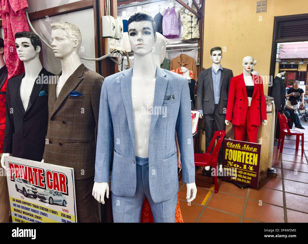 Mannequins exposant des costumes sur mesure pour hommes et femmes dans une vitrine de couture personnalisée située dans les célèbres marchés de tissus de Hoi An, Vietnam Banque D'Images