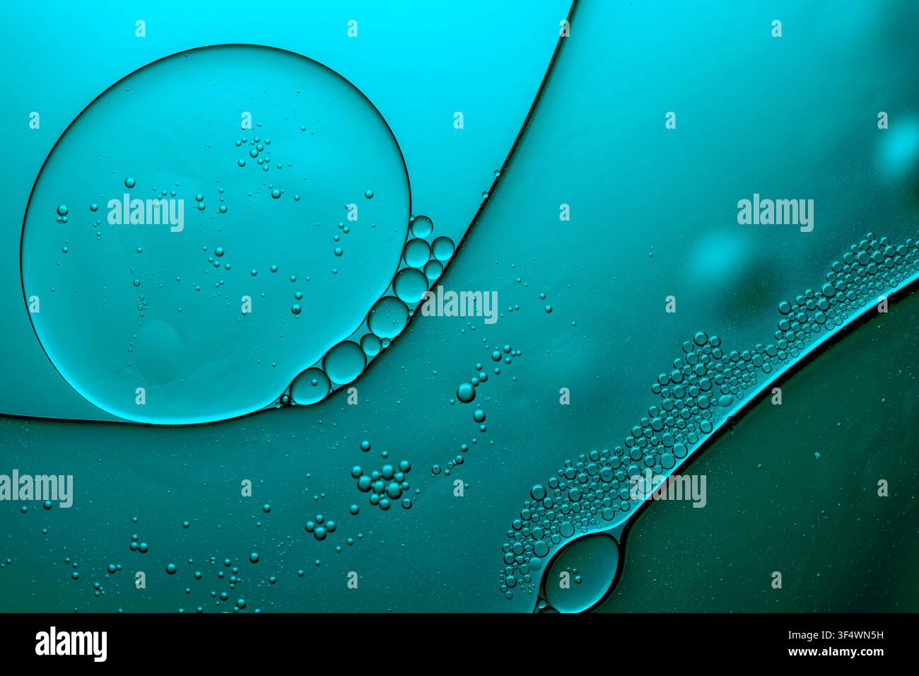 Des gouttes d'huile créant un motif abstrait sur une surface d'eau bleu-vert Banque D'Images