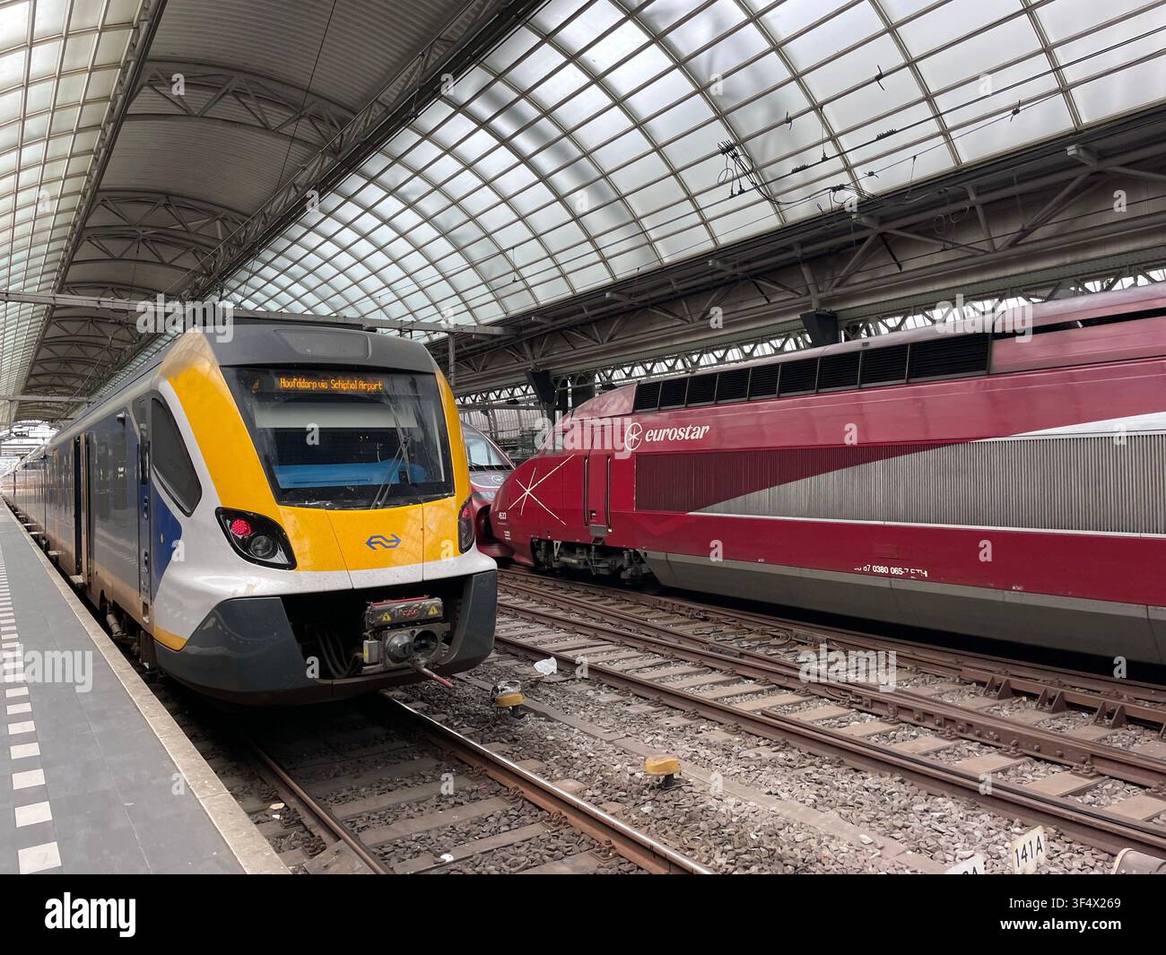 Un train à grande vitesse Eurostar arrive en gare avec un train InterCity prêt à partir à la gare centrale d'Amsterdam Banque D'Images