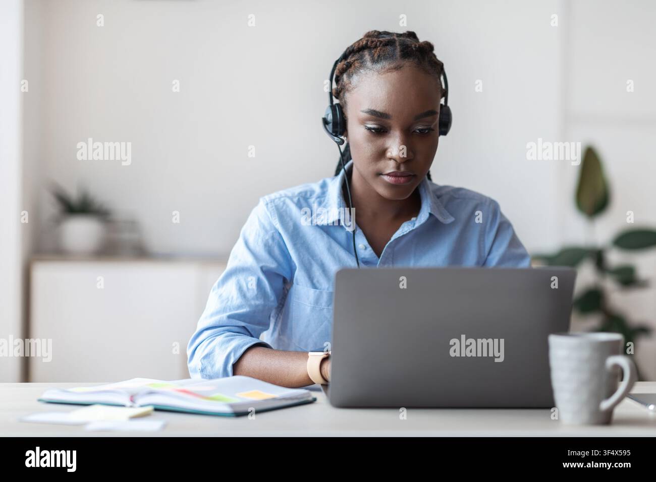 Jeune femme noire de l'opérateur de la ligne directe travaillant avec un ordinateur portable au bureau Banque D'Images