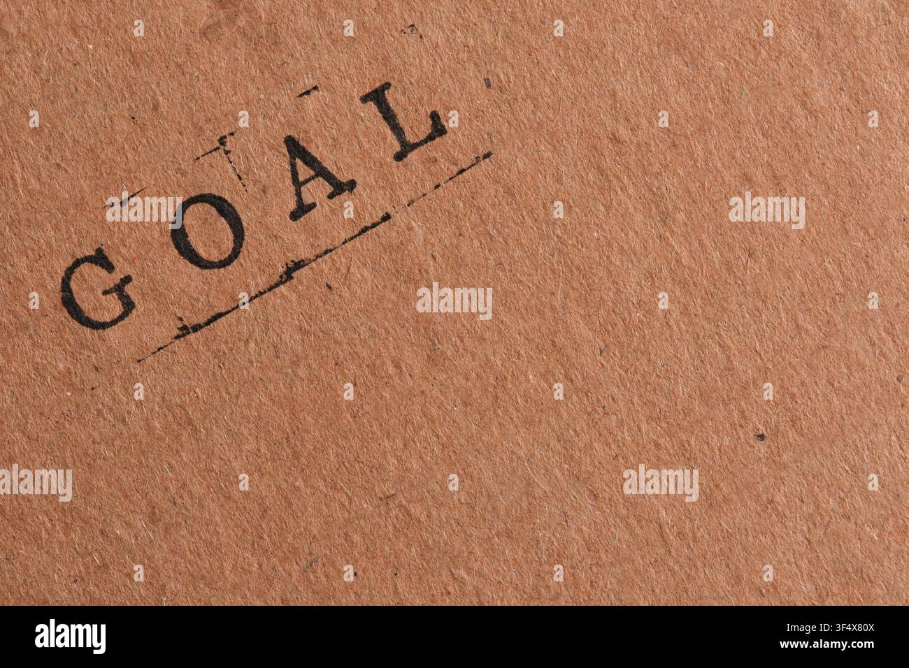 Typographie diagonale avec le mot GOAL tamponné sur du papier kraft marron avec une grande zone d'espace négatif Banque D'Images