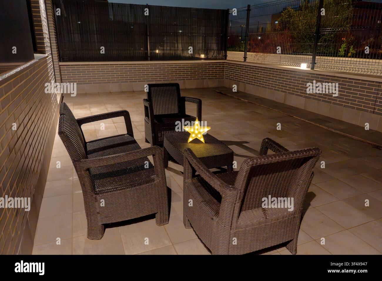 Espace extérieur doté de sièges confortables et d'une étoile illuminée sur une table la nuit Banque D'Images