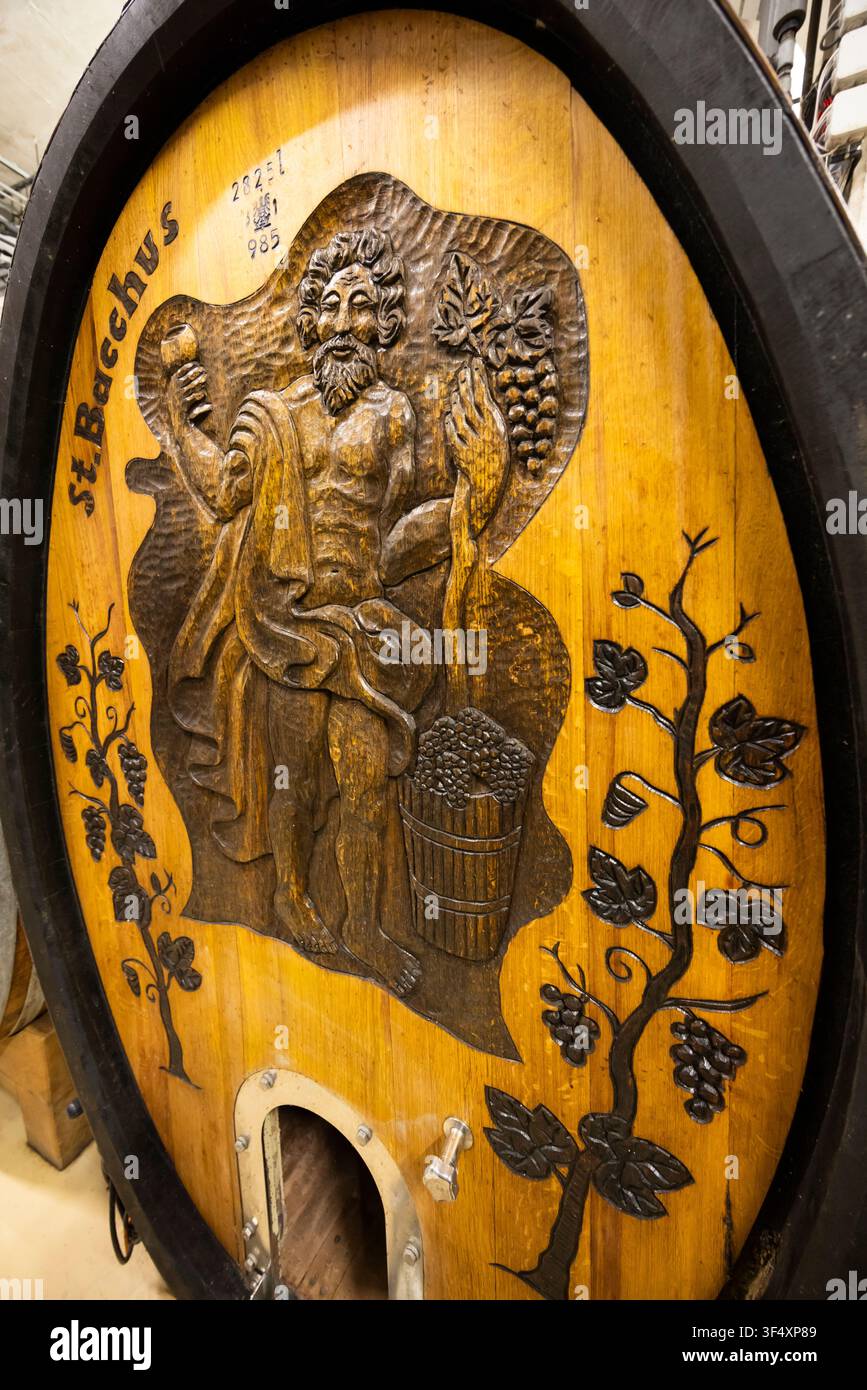 Sculpture en bois de saint Bacchus décorant une tête de tonneau de vin en chêne ancien dans une cave Banque D'Images