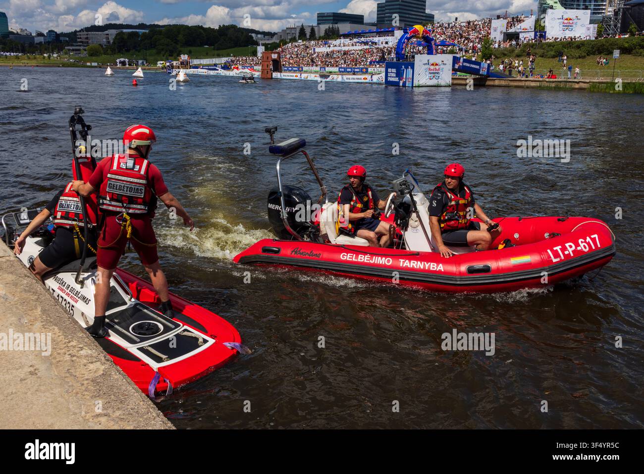Vilnius, Lituanie - 25 juillet 2026 : Vue sur les secouristes dans des bateaux rouges et un jet-ski patrouillant la rivière Neris lors d'un événement public avec des spectateurs Banque D'Images