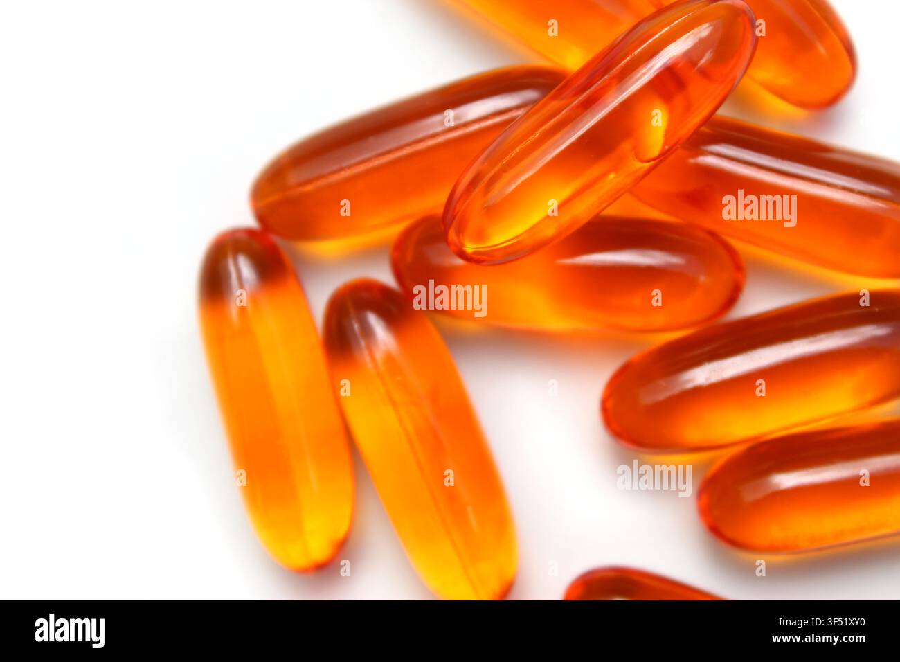 Close-up de pilules dorées (suppléments de vitamine A, D3, E et Oméga-3) empilés sur un fond blanc isolé. Concept : nutrition, jaune, orange Banque D'Images