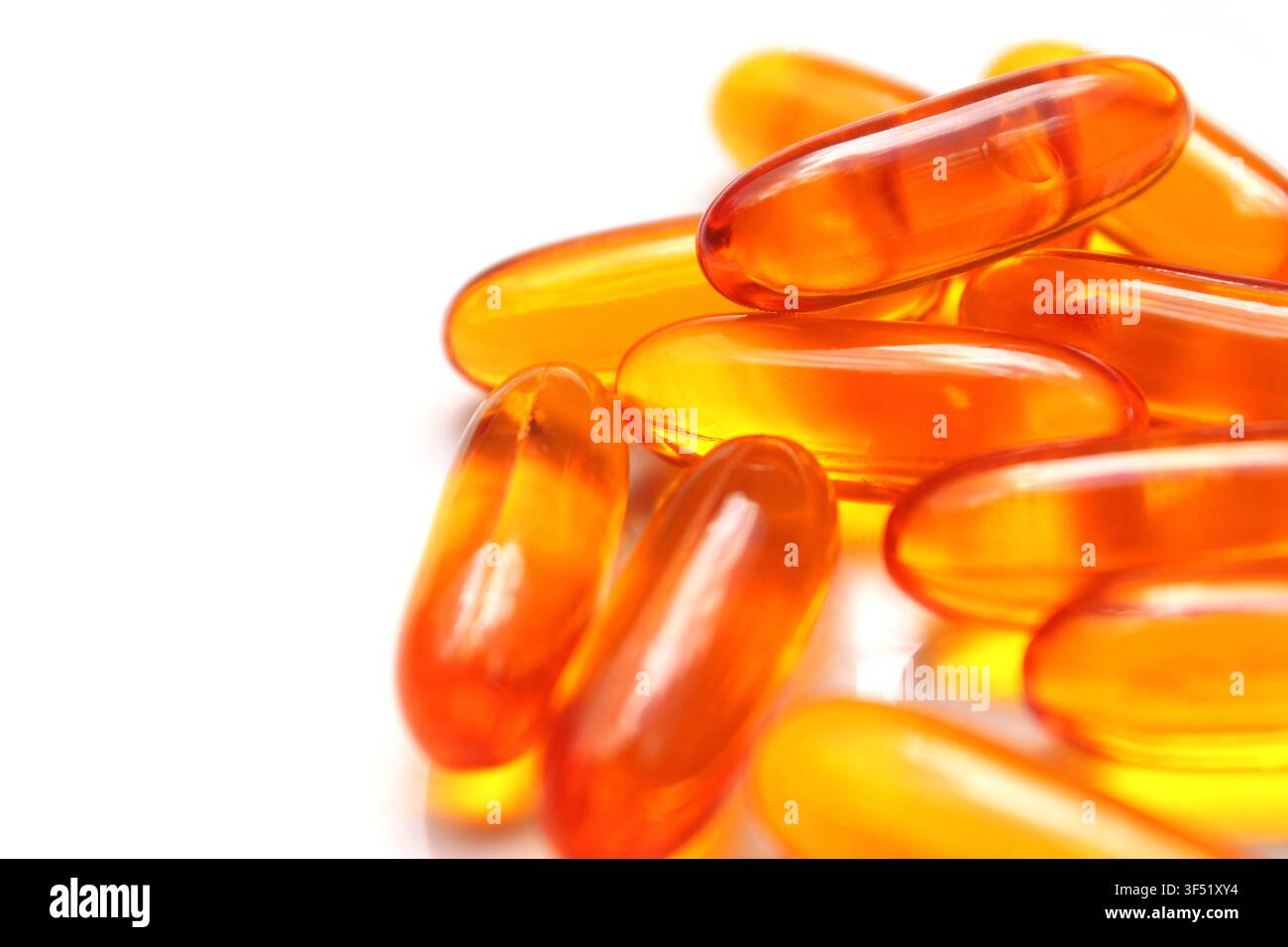 Close-up de pilules dorées (suppléments de vitamine A, D3, E et Oméga-3) empilés sur un fond blanc isolé. Concept : nutrition, jaune, orange Banque D'Images