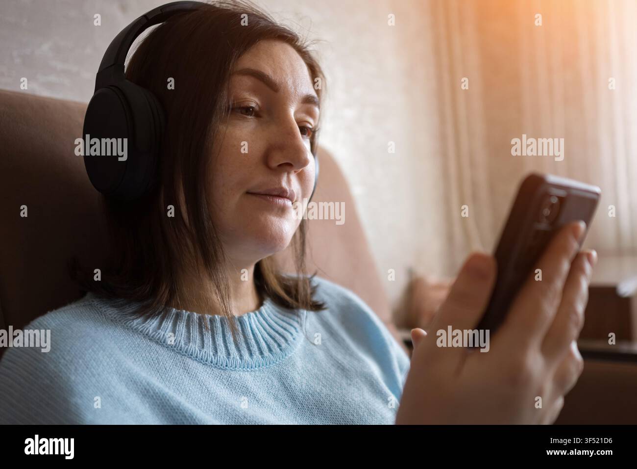 Femme enceinte écoutant de la musique avec des écouteurs tout en utilisant un smartphone à la maison Banque D'Images