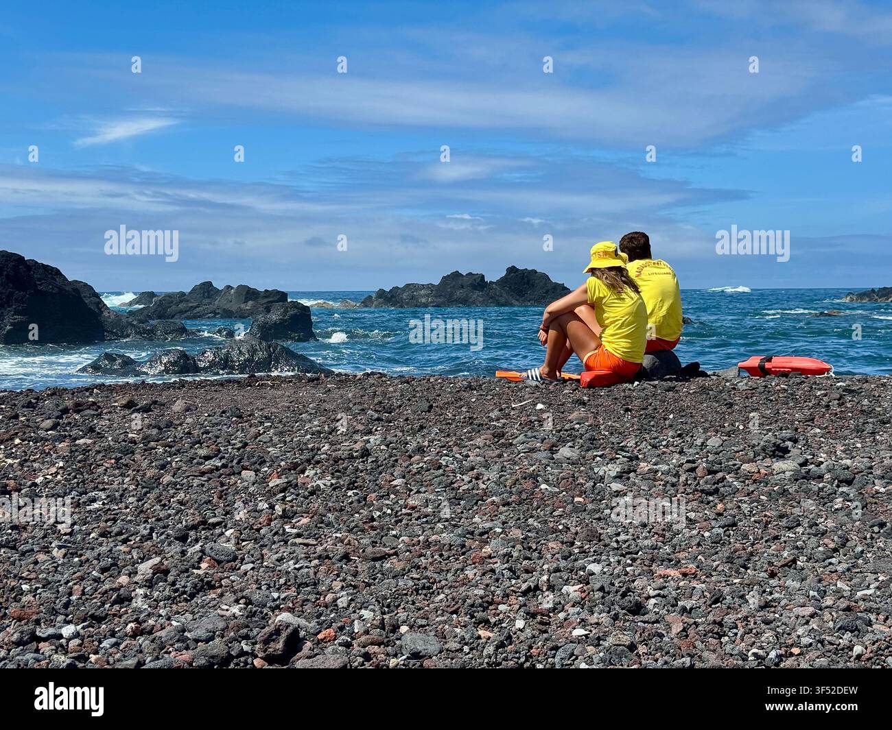 Maîtres-nageurs en service sur la plage de galets volcaniques noirs et les bassins de baignade naturels de Mosteiros, île de São Miguel, Açores. - Image de stock capturée avec un smartphone