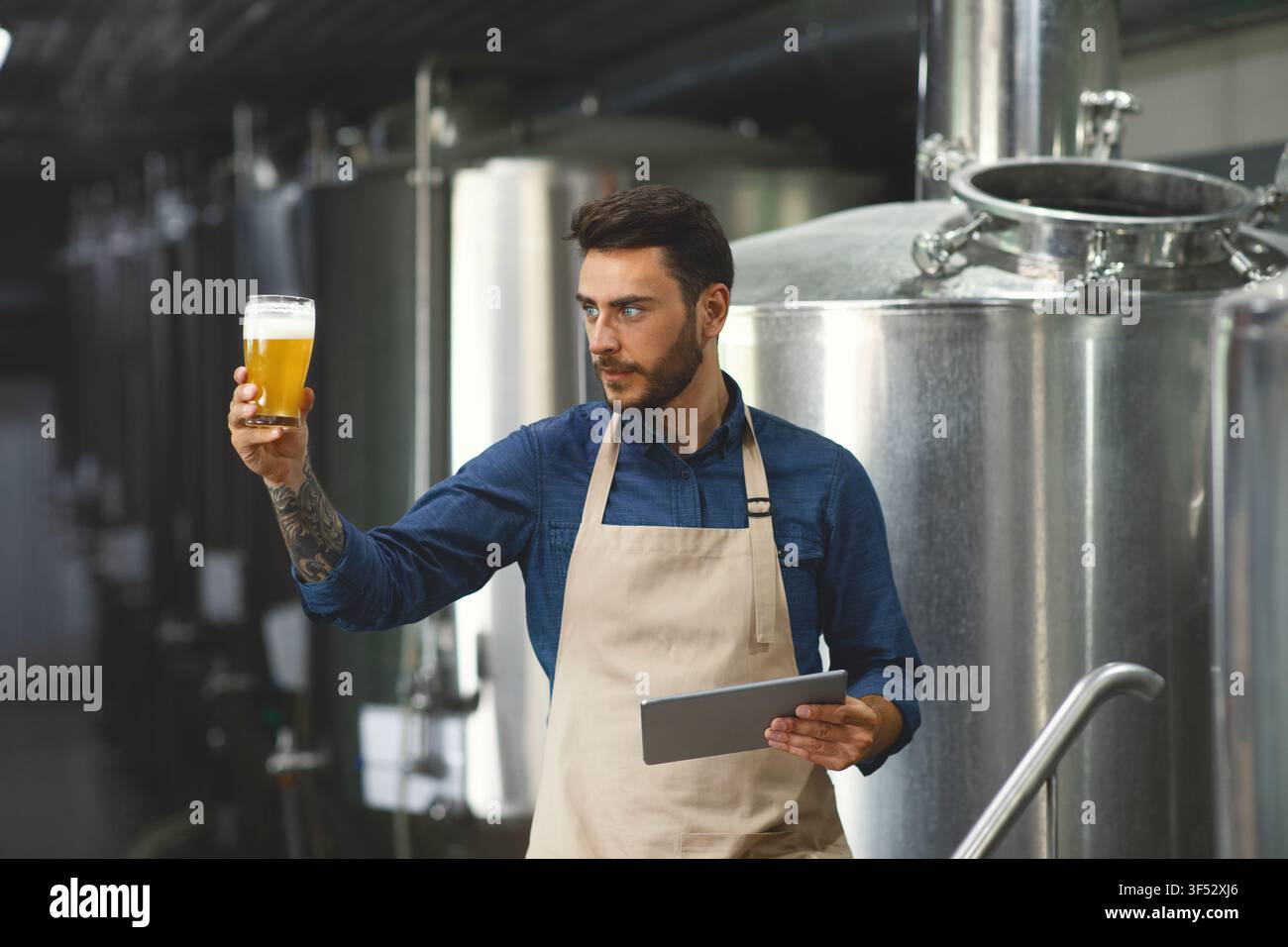 Un brasseur élégant vérifie les boissons à l'usine, travaille chez un spécialiste de la brasserie Banque D'Images