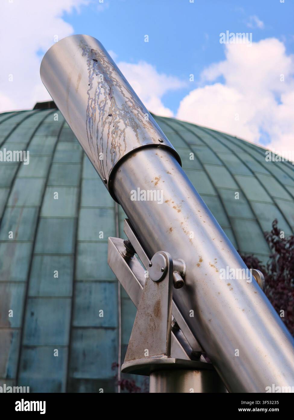 Téléscope métallique en plein air pointé vers le ciel avec un grand dôme de planétarium d'observatoire en arrière-plan Banque D'Images
