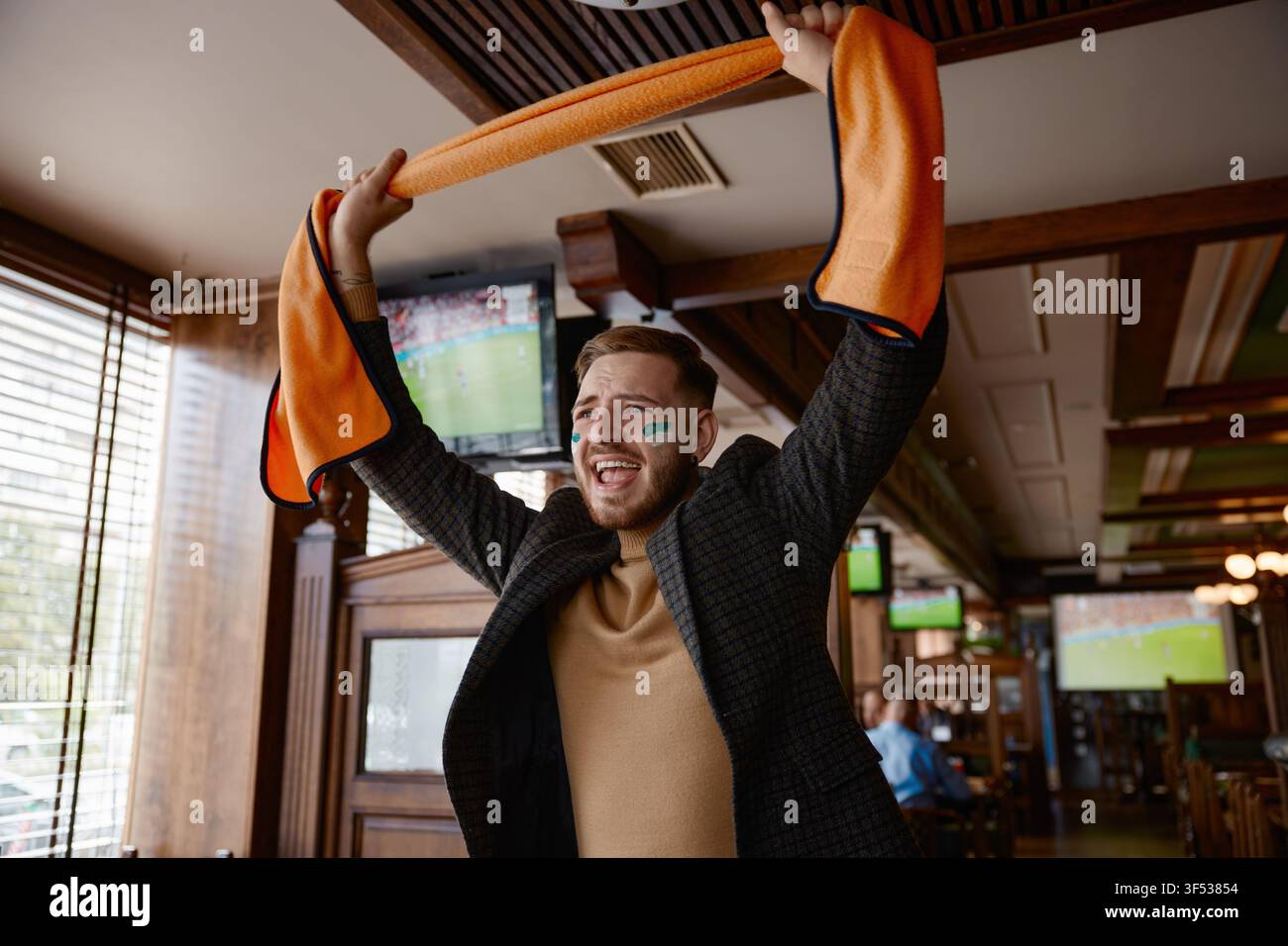 Fan acclame pendant le match en direct. Spectateur enthousiaste célèbre le but dans un pub animé Banque D'Images