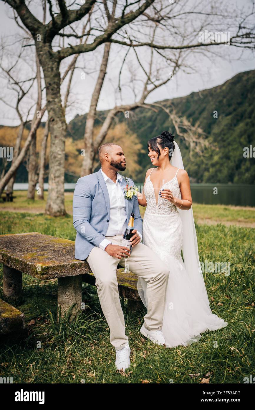 Couple de jeunes mariés célébrant avec du champagne en plein air Banque D'Images