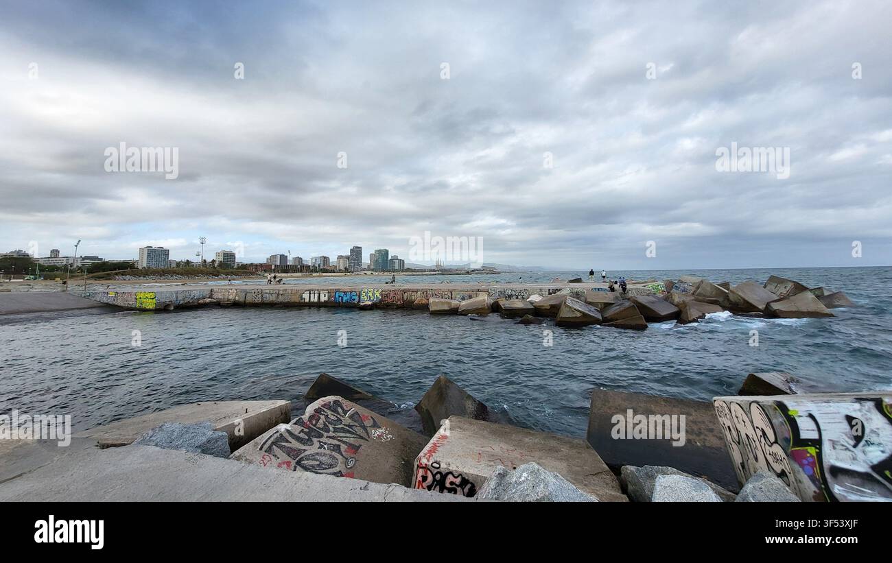 Nuages d'orage sur le front de mer méditerranéen et la digue avec la skyline de Barcelone au loin, Catalogne, Espagne - Image de stock capturée avec un smartphone