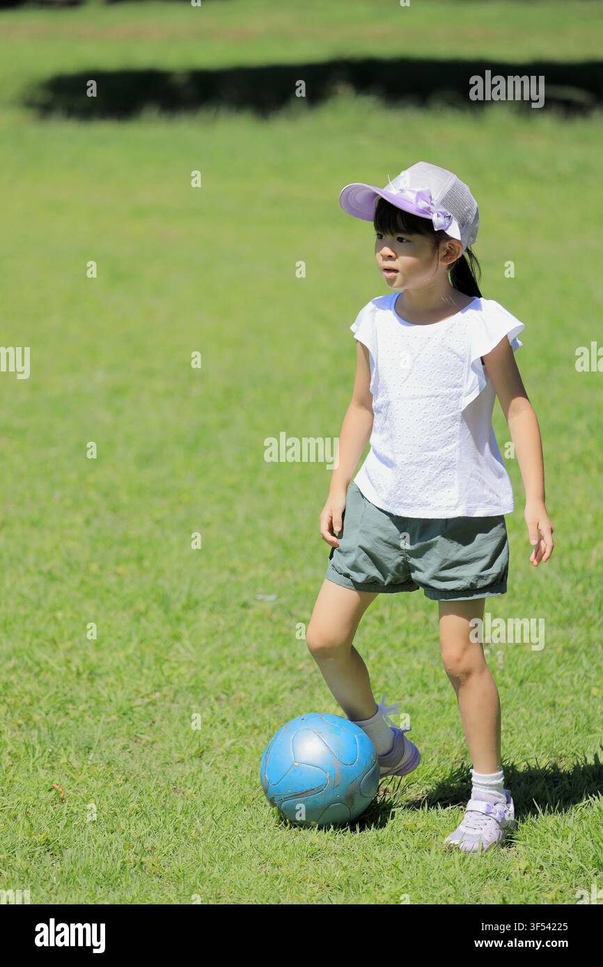 Élève japonaise jouant au football sur l'herbe (6 ans) Banque D'Images