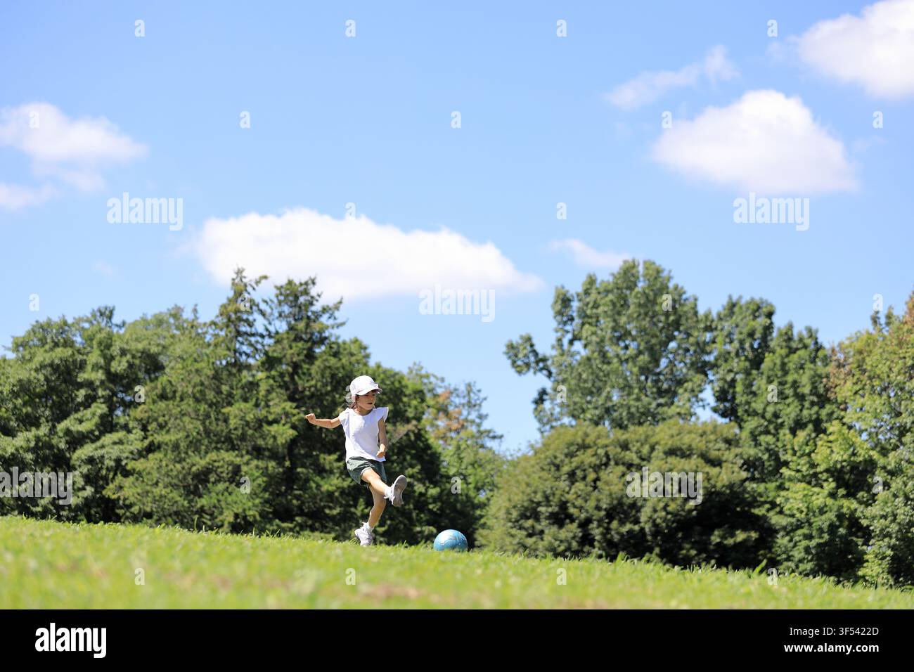 Élève japonaise jouant au football sur l'herbe (6 ans) Banque D'Images