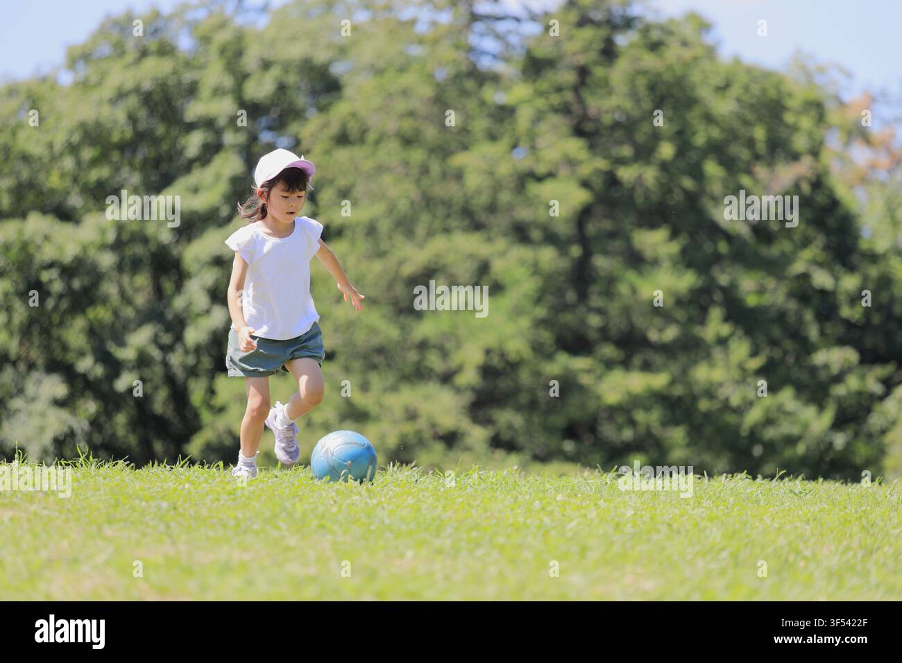 Élève japonaise jouant au football sur l'herbe (6 ans) Banque D'Images
