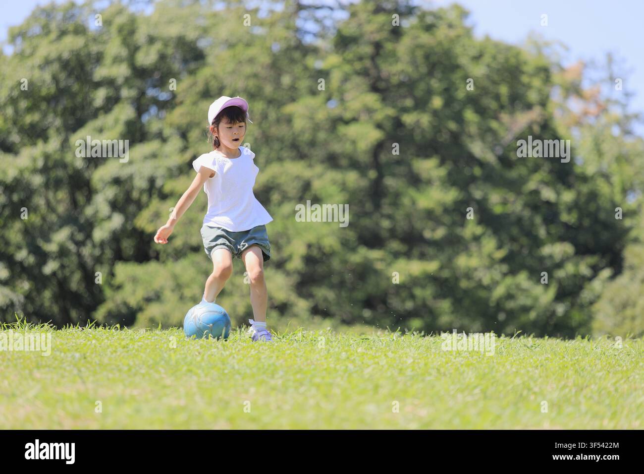 Élève japonaise jouant au football sur l'herbe (6 ans) Banque D'Images