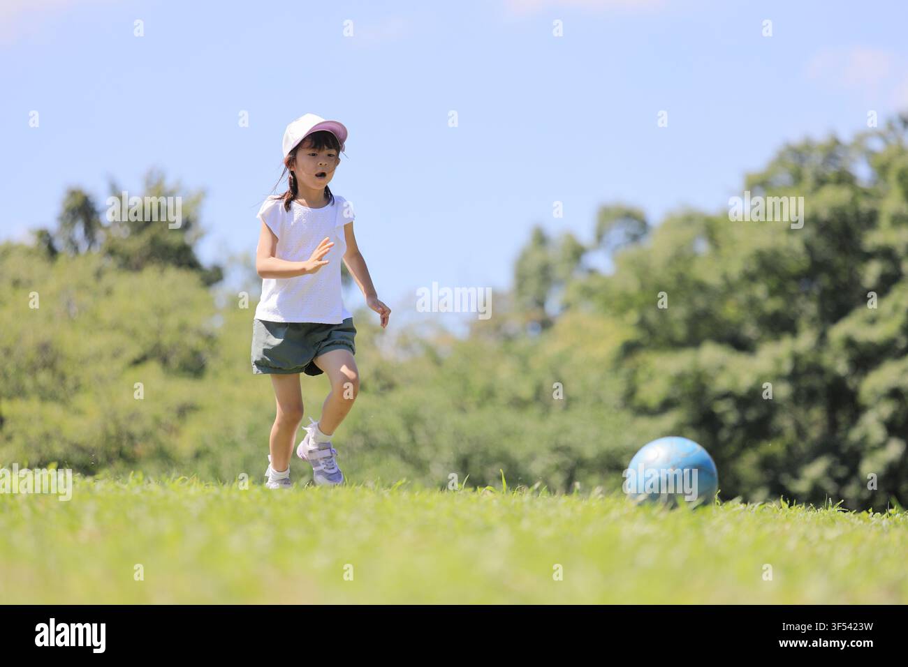 Élève japonaise jouant au football sur l'herbe (6 ans) Banque D'Images