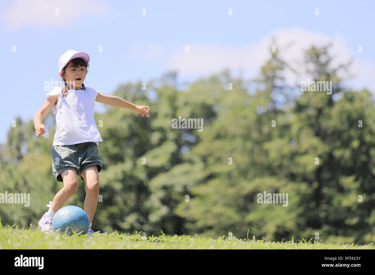 Élève japonaise jouant au football sur l'herbe (6 ans) Banque D'Images