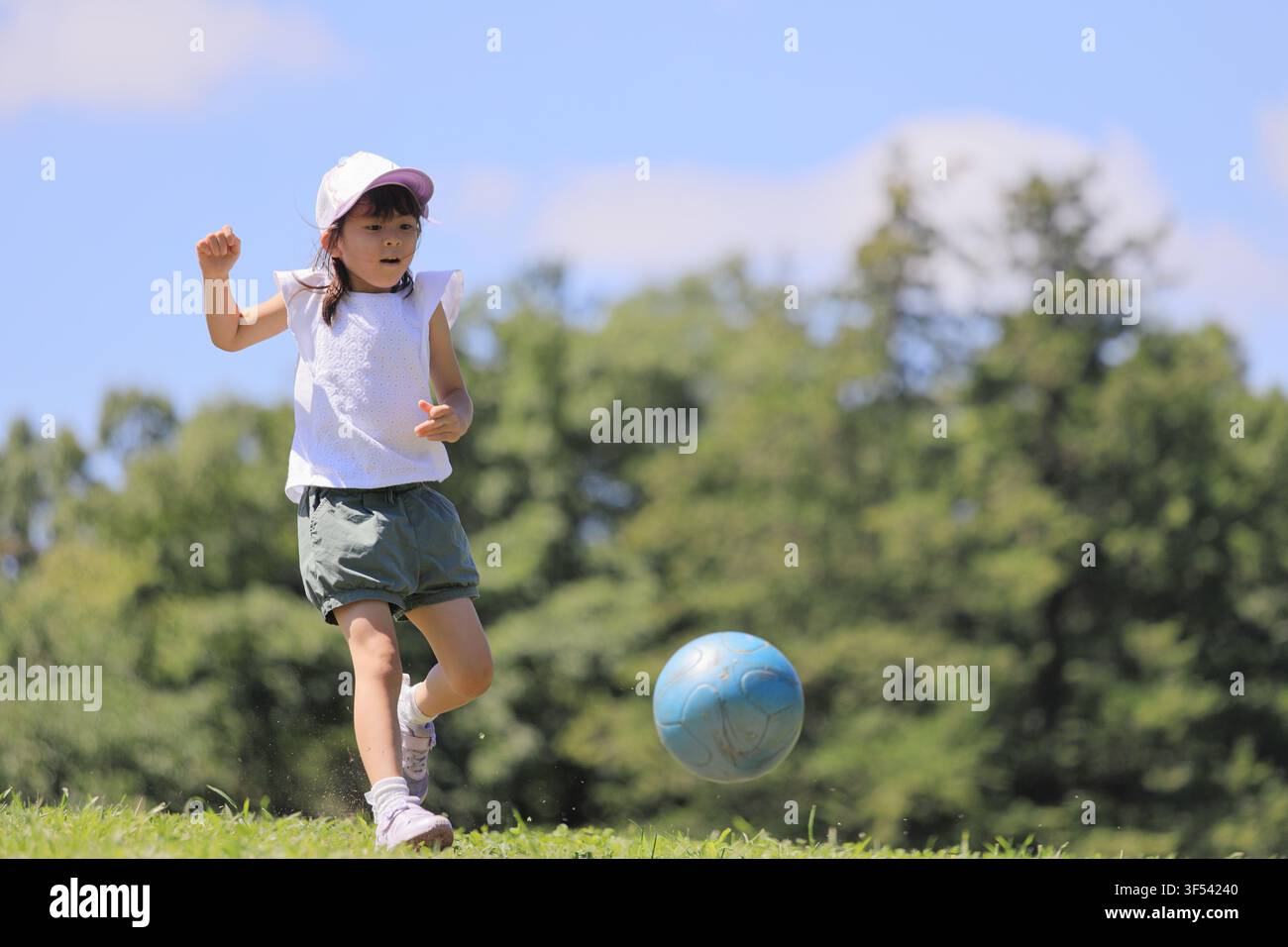 Élève japonaise jouant au football sur l'herbe (6 ans) Banque D'Images