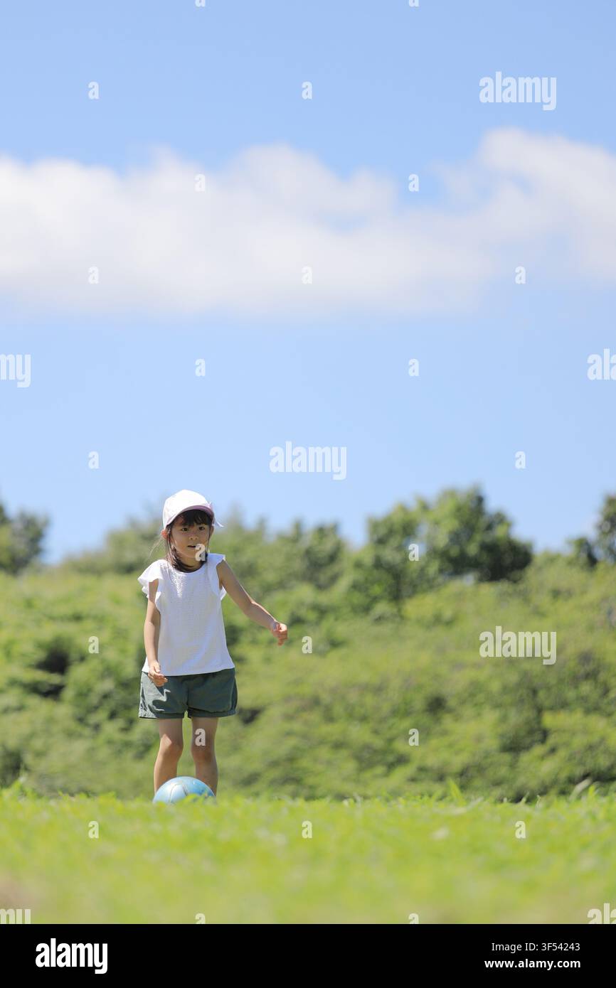 Élève japonaise jouant au football sur l'herbe (6 ans) Banque D'Images