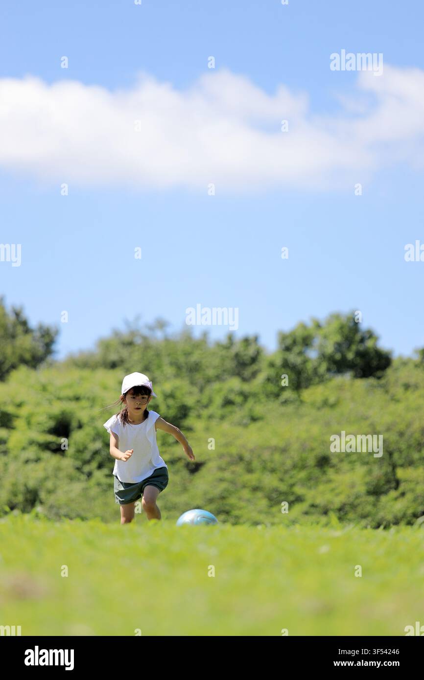 Élève japonaise jouant au football sur l'herbe (6 ans) Banque D'Images
