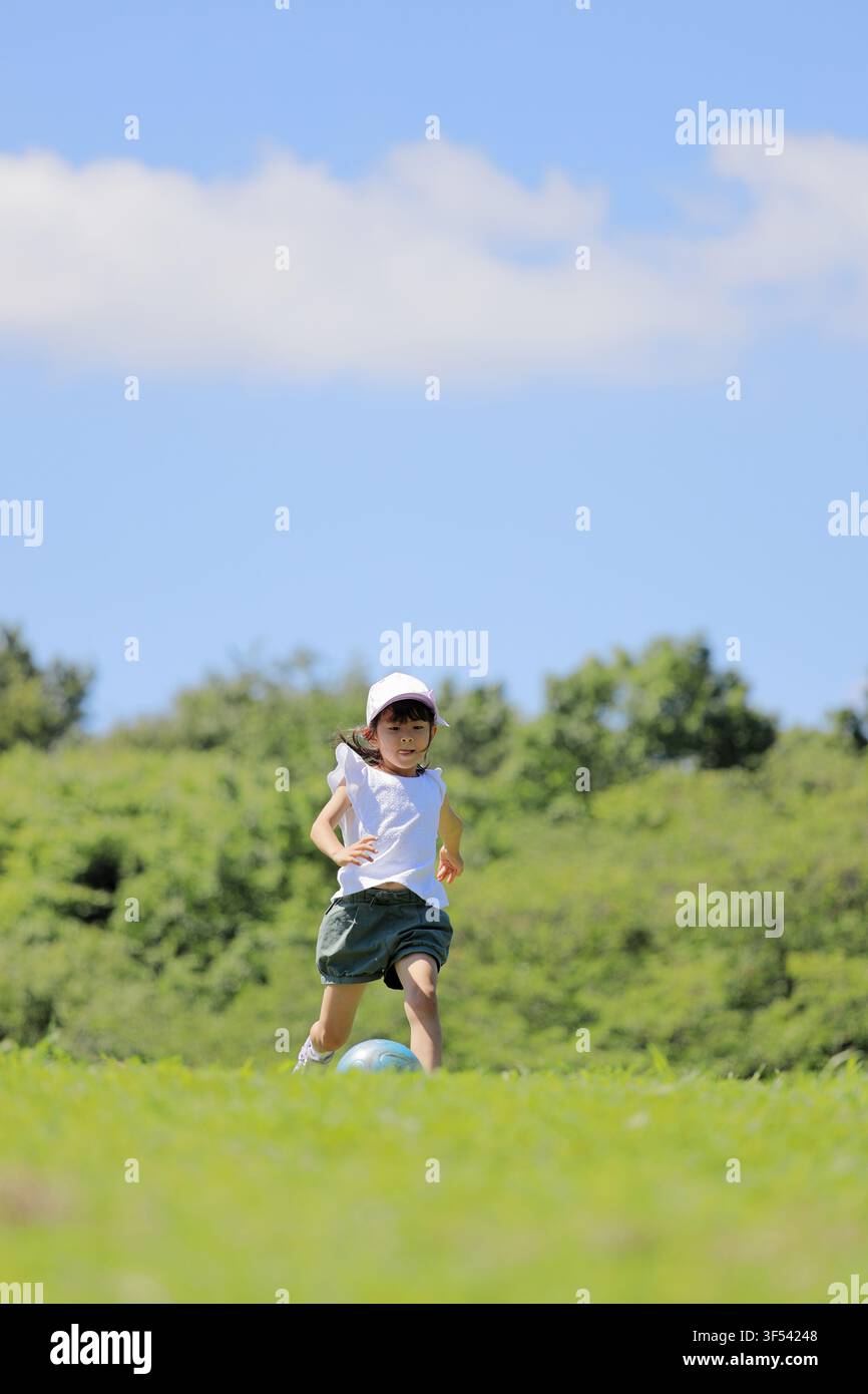 Élève japonaise jouant au football sur l'herbe (6 ans) Banque D'Images