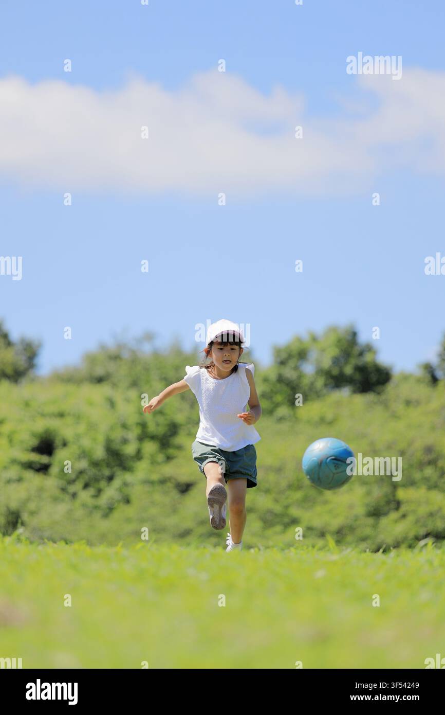 Élève japonaise jouant au football sur l'herbe (6 ans) Banque D'Images