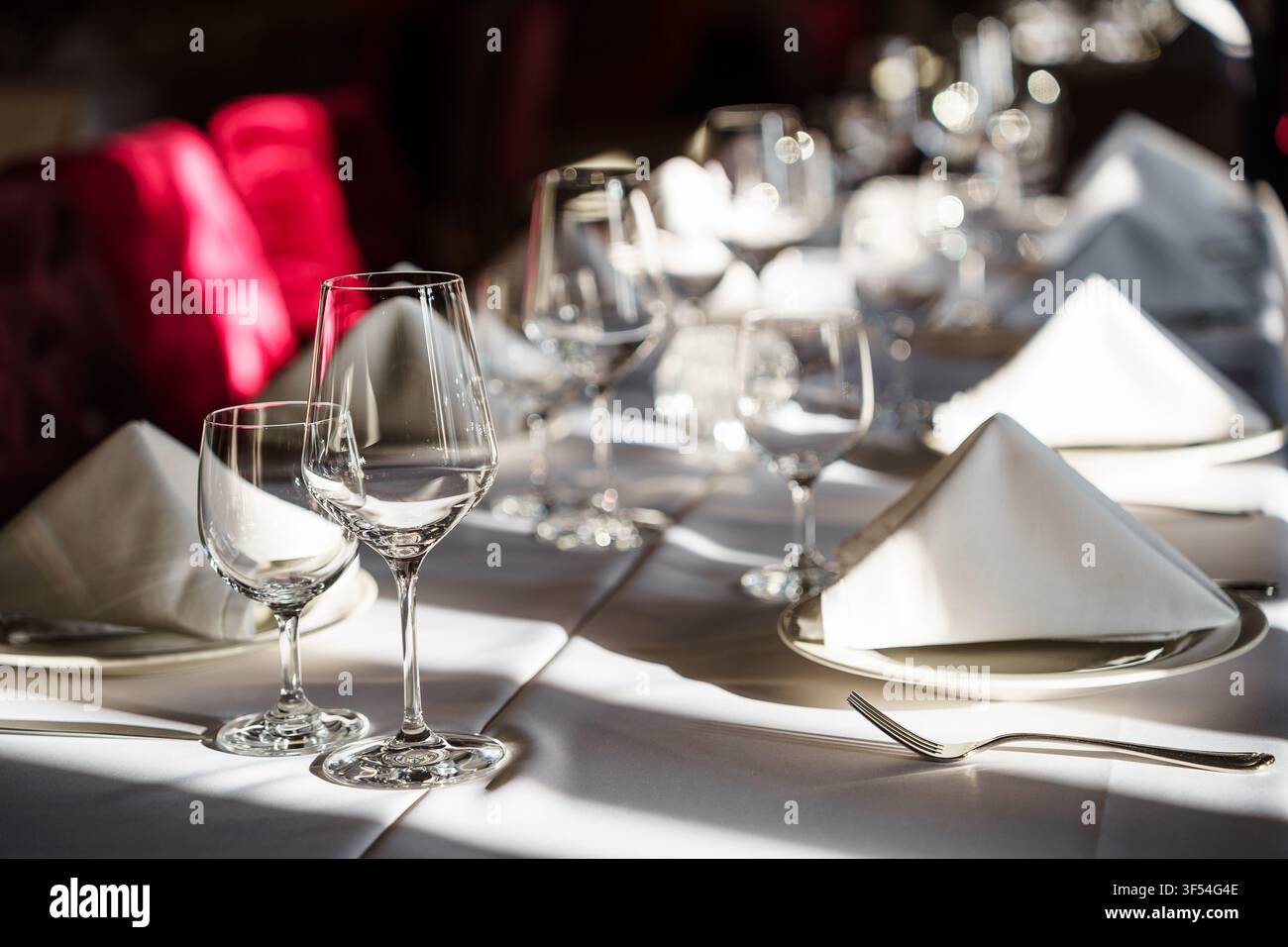 Élégante mise en place de table de restaurant avec des verres à vin en cristal et des serviettes blanches pliées sur une table à manger formelle pour des événements de luxe et une cuisine fine Banque D'Images