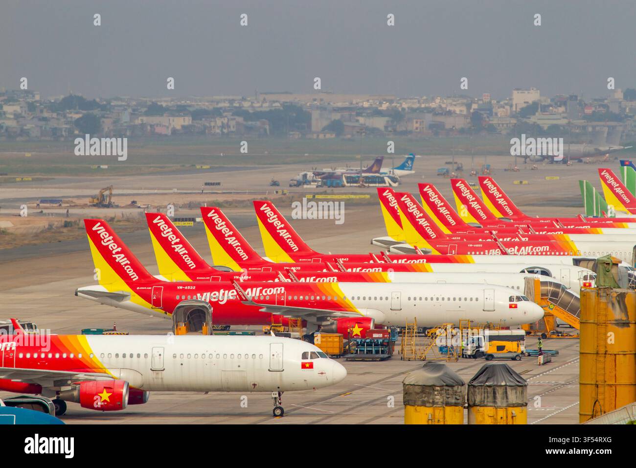 Range d'avions de ligne commerciaux Vietjet Air garés sur le tarmac de l'aéroport international de Tan Son Nhat à Ho Chi Minh Ville, Vietnam. Banque D'Images